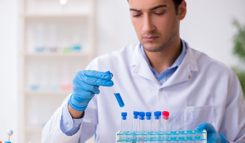scientist in lab coat inserting liquid-filled vial into tray